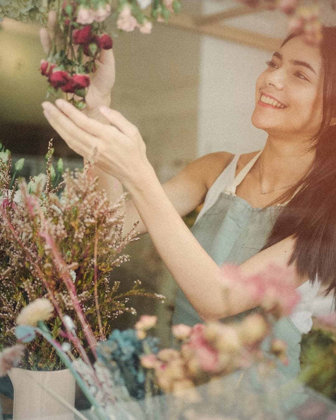 A florist smiling as she arranges flowers